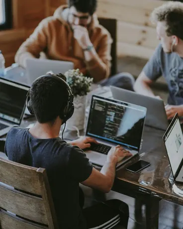 A small team working together around a table of laptops
